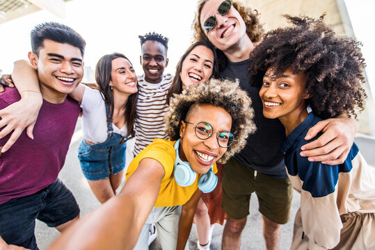 Multicultural happy friends having fun taking group selfie portrait on city street - Multiracial young people celebrating laughing together outdoors - Happy lifestyle concept.