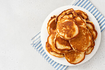 Homemade pancakes in a white plate on a gray concrete background top view.  Copy space for text. Tasty breakfast