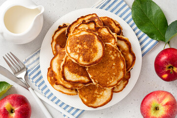 Homemade apple pancakes in a white plate on a gray concrete background top view. Tasty breakfast