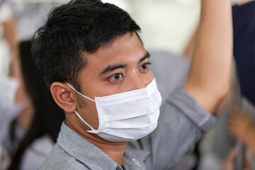 Asian businessman wearing face protective mask for protection from virus disease while standing on subway train, public transport during coronavirus, COVID 19 outbreak. health, safety