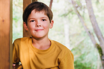 Portrait of a boy of eight years old in a yellow T-shirt. A boy with dark hair stands on the...
