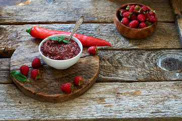 raspberry sauce with chili. Wooden background, side view.