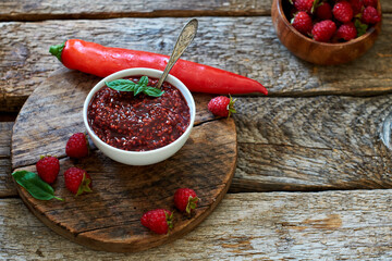 raspberry sauce with chili. Wooden background, side view.