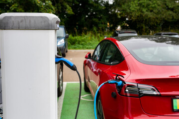 Electric car charging at plug in charge station in a public car park in Suffolk, UK