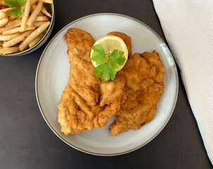 Austrian Art chicken schnitzel with french fries and lemon.