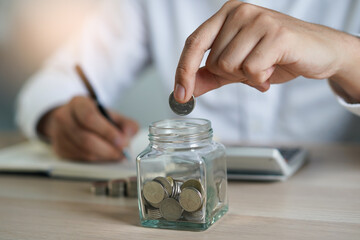 Close up hands of man putting coins into piggy bank