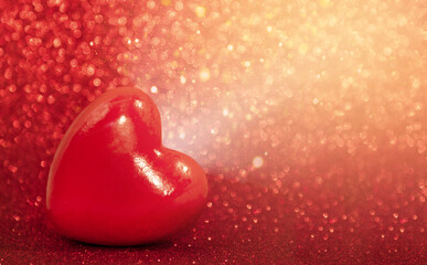 Fototapeta premium Red heart on a red shiny background with light