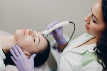 Naklejka premium Close up of head woman receiving electroporation phonophoresis facial therapy at beauty spa salon