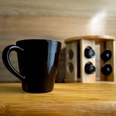 Xícara de café sobre a madeira com cápsulas de café ao fundo 