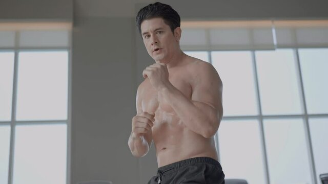 Athletic muscular topless man practicing box and protection with footstep moving at the fitness. combat fighting exercise. boxing sport concept. 4K slow motion