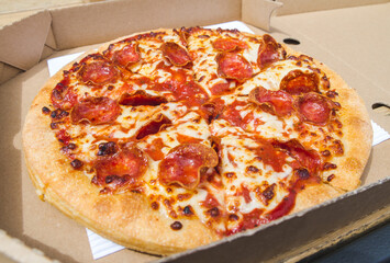 Delicious pepperoni pizza in a folding cardboard box. Tasty fast food takeout to-go.