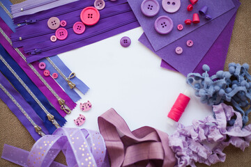 Handicraft materials; pink and purple felt, ribbons and buttons on white background