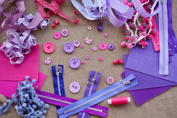 Handicraft materials; pink and purple felt, ribbons and buttons are scattered
