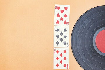 An old vinyl record and lucky three eights in cards