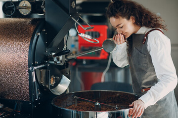 Coffee roaster machine and barista smell roasted beans during coffee roasting process.