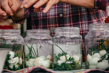 authentic photo of soiled female hands of elderly woman, cooking canned vegetables from harvest in kitchen, putting in glass jars