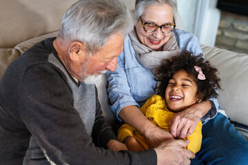 Portrait of happy grandparents with child playing together at home