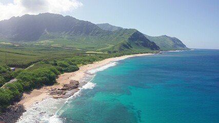 Aerial shot on the beach of Oahu Hawaii. Dream trip to green island. Outdoor adventure travel to beautiful Hawaii beach. Cinematic wild nature. Slow motion waves of transparent green sea waters.