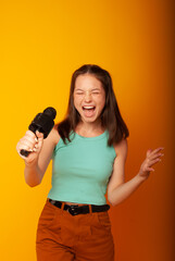 girl brunette teenager, 15 years holding a microphone in his hands depicting singing with his mouth open. The concept of postcards or a vocal lesson at school, back to school