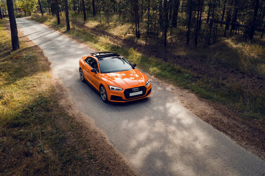 Samara, Russia - 09.05.2020: Orange AUDI A5 S line. A modern sports orange car is parked on a forest road. Travel concept. Pine forest at the sunset. Bird's-eye view