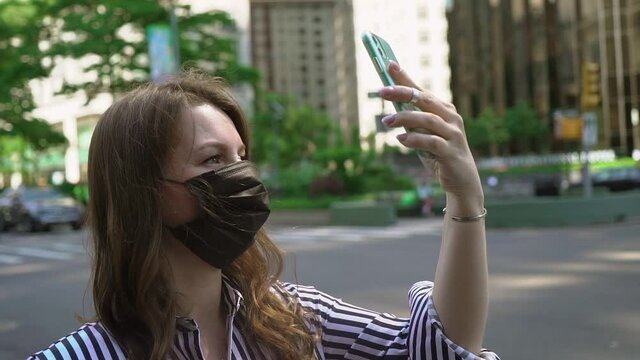 Girl makes photos or videos on a mobile phone. Young woman in New York City.