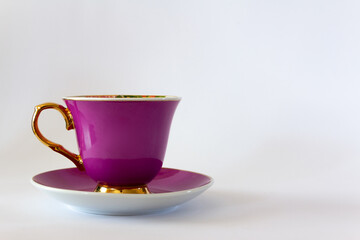 Pink tea or coffee cup with gold trim on white background. Selective focus. Copy space.