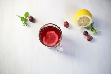 Glass of homemade compote of plums, lemon, mint on white background