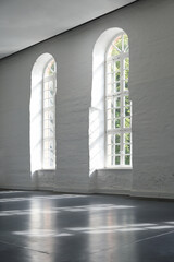 Two long arched windows in a white painted brick wall indoors in a large historic building, architecture and interior concept, copy space, selected focus
