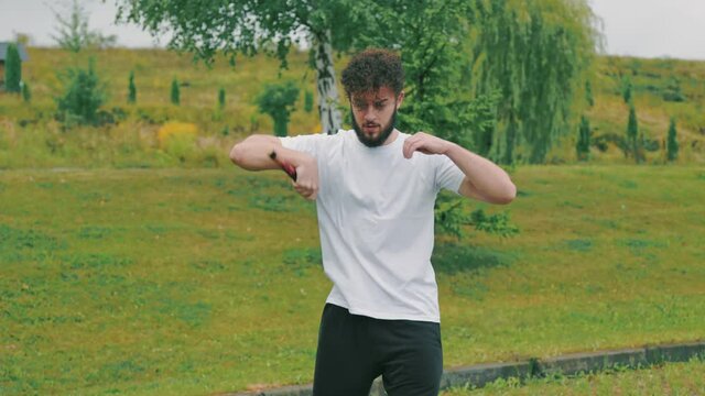 man twists nunchucks in nature