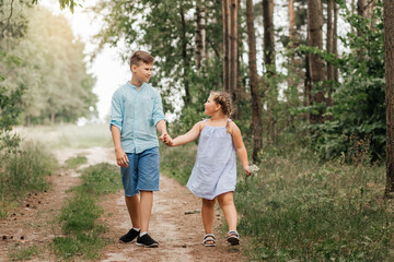 A boy and a girl, brother and sister walk along a forest path together