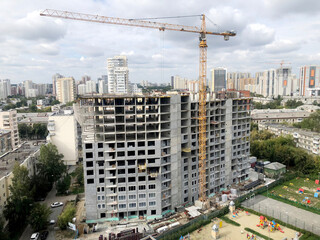 construction of a multi-storey residential building in the city with a tower crane in daylight