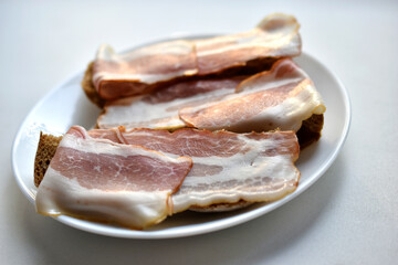 Fresh juicy bacon on a piece of rye bread