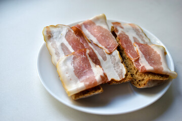 Fresh juicy bacon on a piece of rye bread