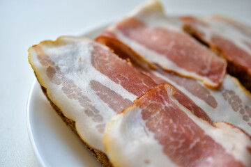 Fresh juicy bacon on a piece of rye bread