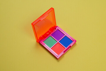 Purple, green, orange and blue eye shadow palette on a green background. Make up. Neon colours.