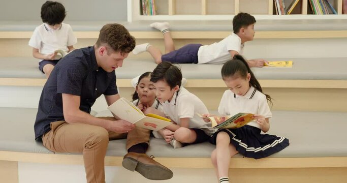 Foreign teacher and children reading book in library,4K
