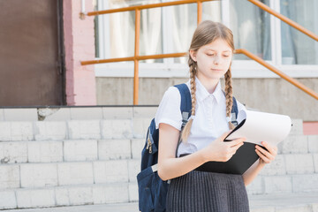 Product advertising. Happy small school age child presenting your product. Little girl with books...