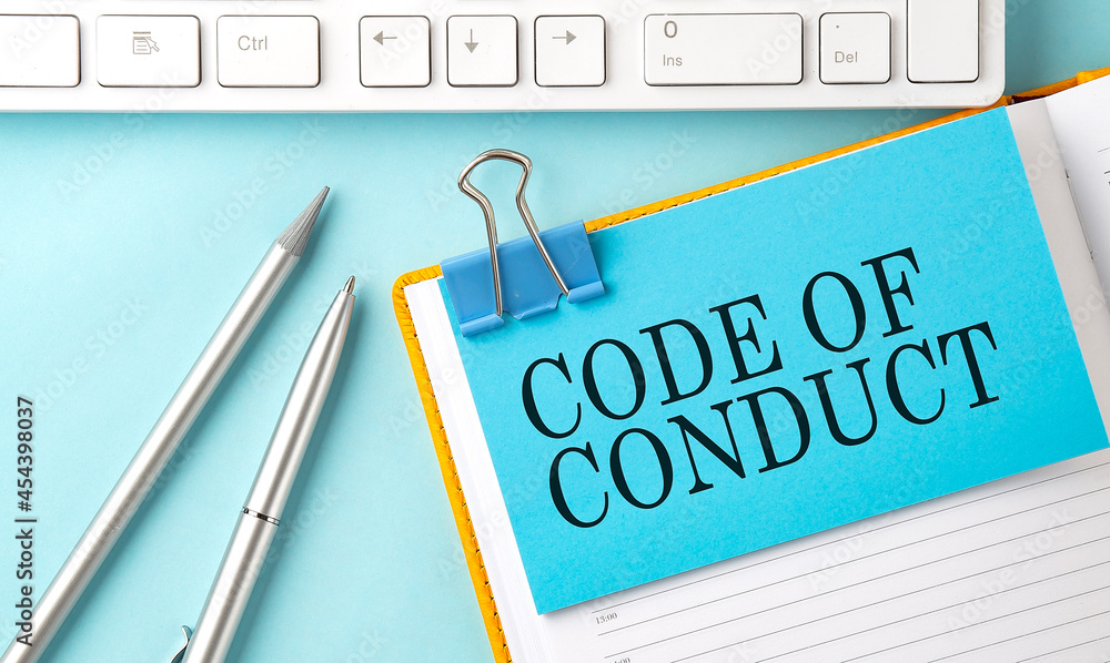Poster code of conduct text on sticker on the blue background with pen and keyboard