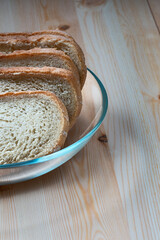 slices of white wheat bread in a glass bowl on a light wooden surface