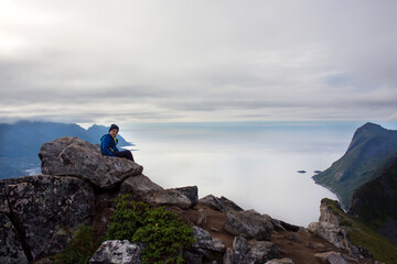 Cute child, standing on a rock and looking over Segla mountain on Senja island, North Norway. Amazing beautiful landscape and splendid nature in scandinavian country