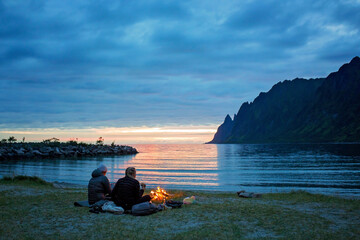People, enjoying fireplace on the beach, wild camping on Ersfjord beach in Senja national park in  northern Norway