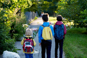 Happy children, going to school in the morning, first day, caring bouquet of flowers for the teacher