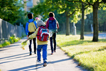 Happy children, going to school in the morning, first day, caring bouquet of flowers for the teacher