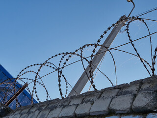 Barbed wire on top of the wall of the regime object. Barrier for criminals.
