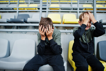 Oh no, they lost the game! Two brothers support their favorite team, sitting on the sports podium...
