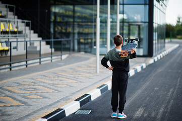 Teenager boy in a sports suit with longboard.