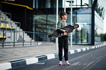 Teenager boy in a sports suit with longboard.