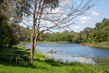 View of the river from the bank on a summer day. An ideal place for fishing among the shores in the green of the trees. Summer sunny day on the river.