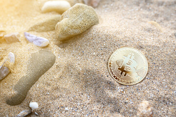 Bitcoin on the beach sand with shells and stones. Single golden BTC crypto coin banner in warm tones with copy space top view. Environment impact of mining cryptocurrency concept.