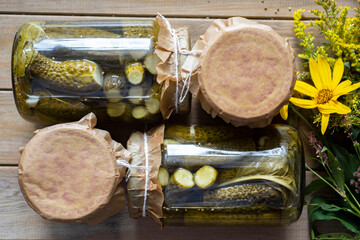 Winter preservation: pickled cucumbers with coriander in glass jars on a wooden table. Top view